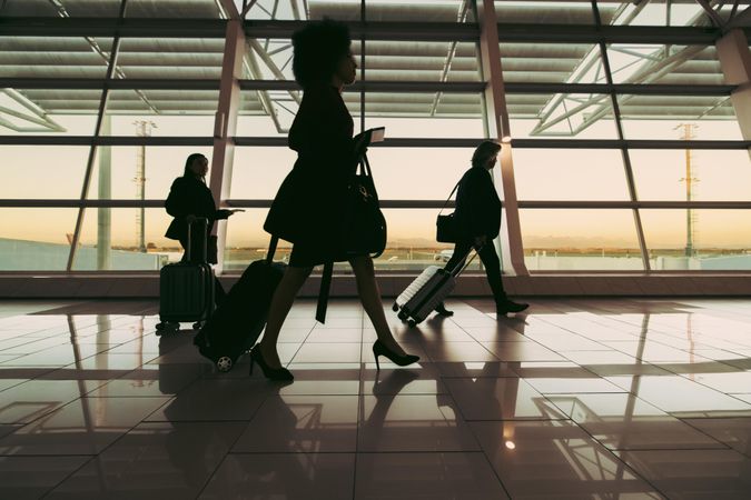 Travelers walking in front of large window at airport terminal