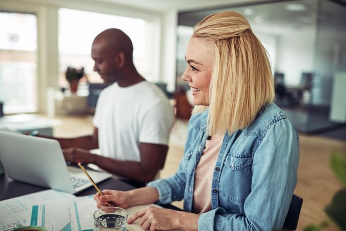 Blonde woman smiling across at her colleagues at work