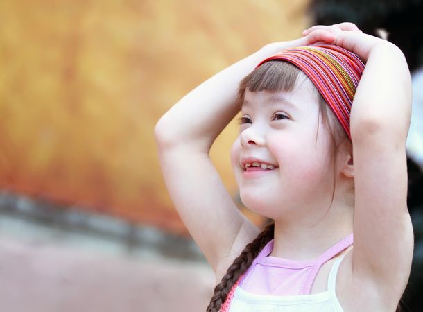 Portrait of a girl with Down syndrome in a pink headband