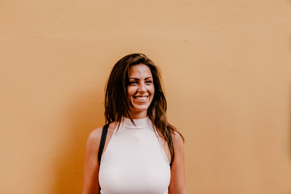 Young brunette standing against orange background