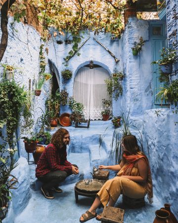 Man and woman drinking tea in a blue house in Chefchaouen, Morocco 