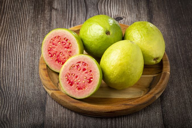 Fresh sliced guavas on wooden table.