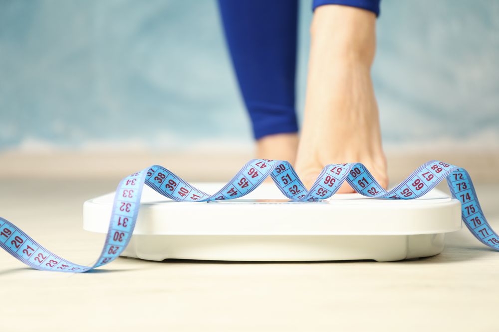 Woman stands on the scales. Measuring tape. Weight loss