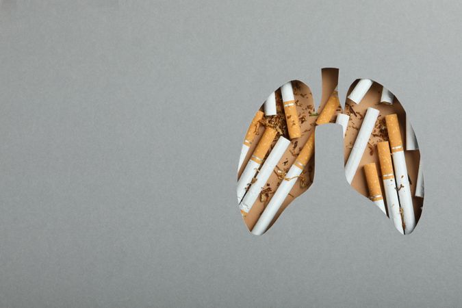 Lung shape cut out of grey paper with cigarettes with space for text