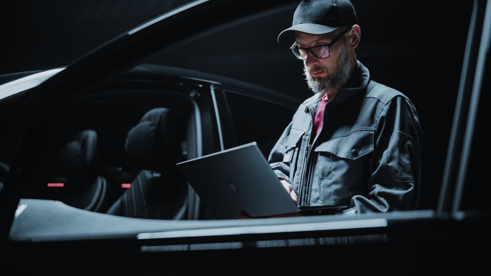 Portrait of a Dealership Car Mechanic Analyzing Diagnostics Results on a Modern Electric Vehicle.