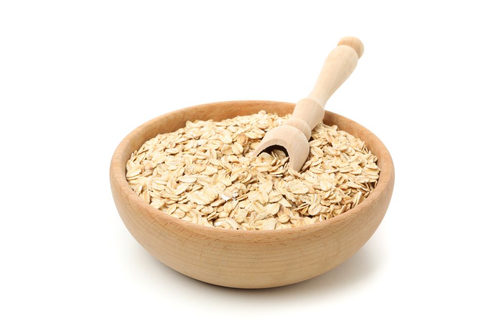 Bowl and scoop with oatmeal flakes isolated on plain background