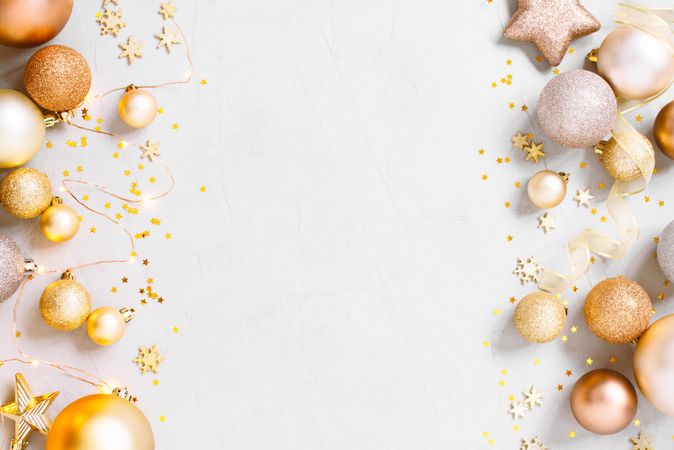 Golden Christmas baubles surrounding beige background with copy space