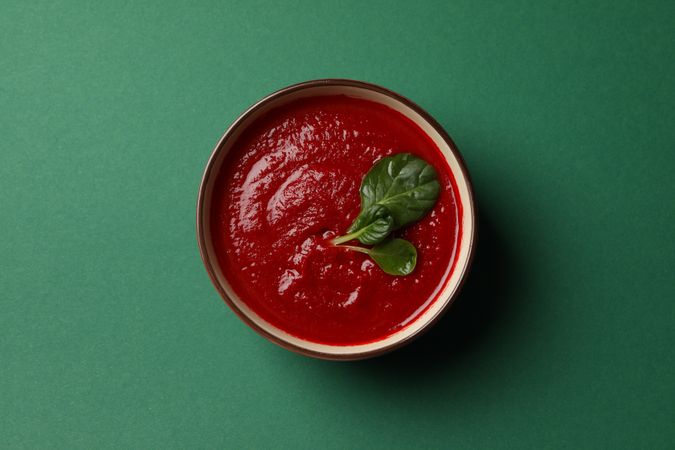 Looking down at bowl of tomato soup on green table