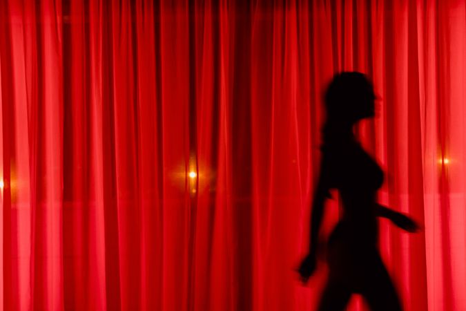 Anonymous woman walking behind curtain