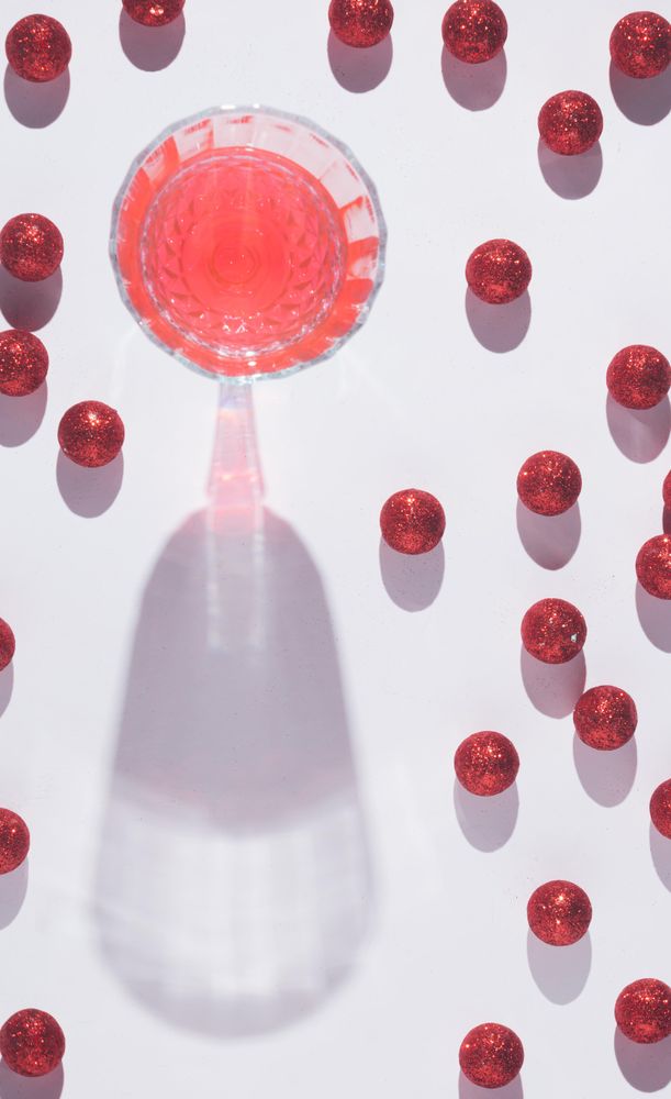 Top view of wine glass surrounded by red Christmas ornaments