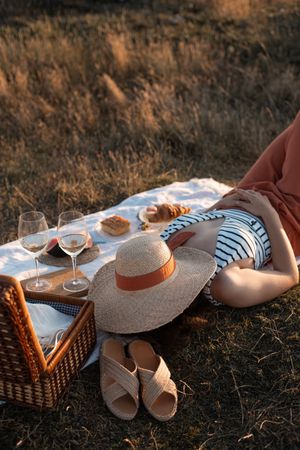 Woman resting in meadow on picnic covering face with hat