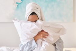 Woman hugging pillows in bedroom