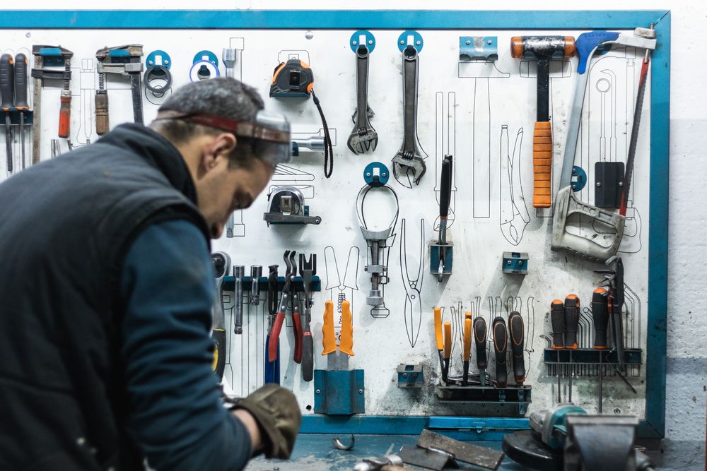 Professional mechanic using spanner while assembling vehicle engine details at workbench