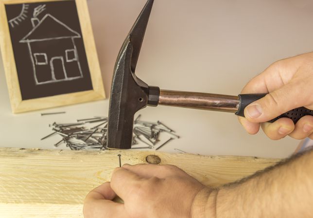 Mans hand hammering nail in wood