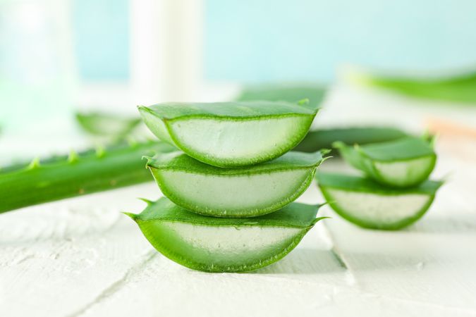 Aloe vera slices on white wooden table, closeup and space for text. Natural treatment