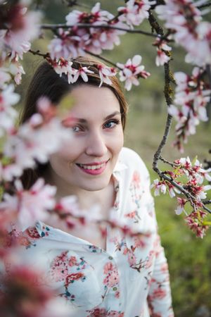 Young happy woman between trees in garden