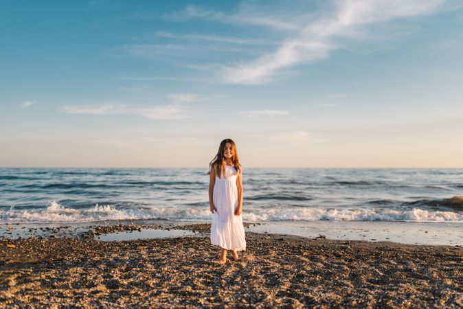 Smiling girl standing on seaside among waves
