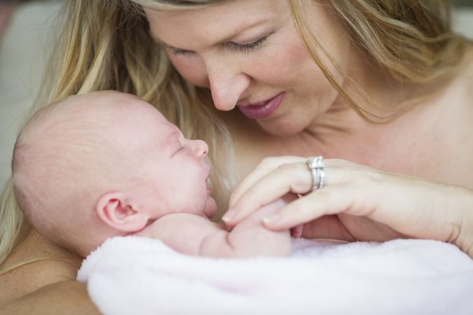 Young Content Mother Holding Her Precious Newborn Baby Girl