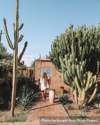 Woman standing beside house and cactus trees 5ryxM0