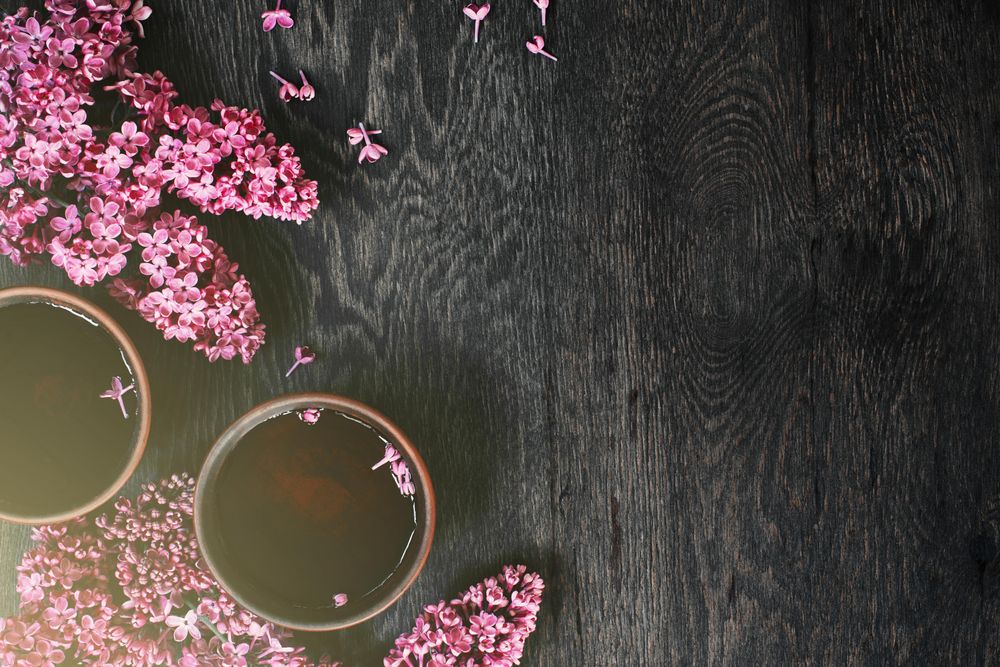 Top view of lilac flowers and two cups of tea with copy space