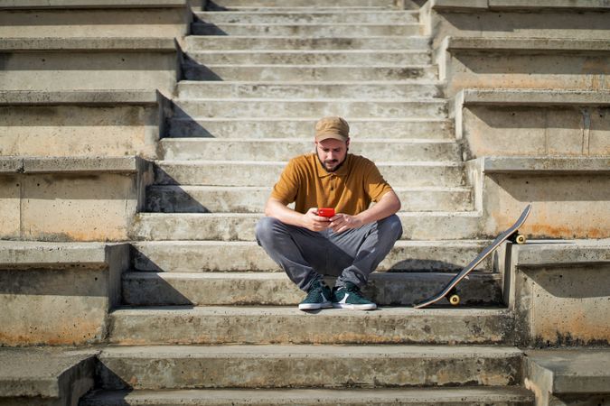 a young man sitting on some steps using his smartphone