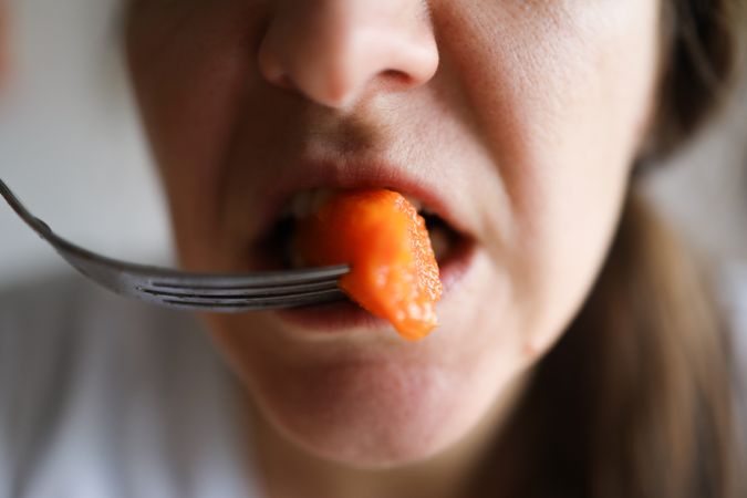 Close up Shot Of a Woman Chewing on a healthy Carrot.