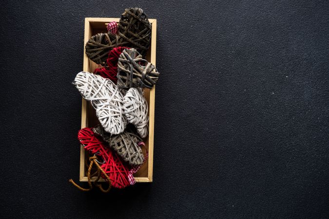 Box of thatched heart ornaments on dark counter