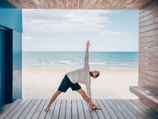 Man doing yoga by the beach
