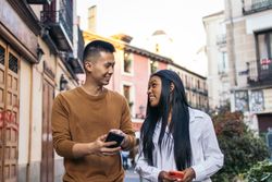 Interracial couple walking down the street using smartphone