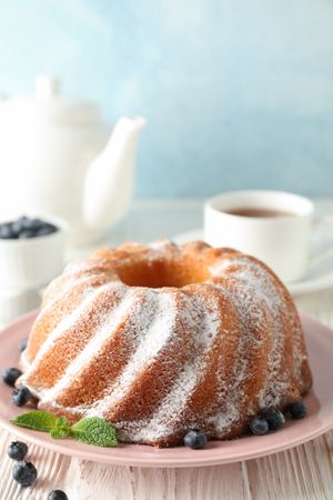 Cake with powder sugar and blueberry on wooden background, space for text