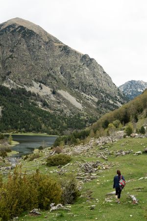 Unrecognizable traveling woman in green valley near mountains