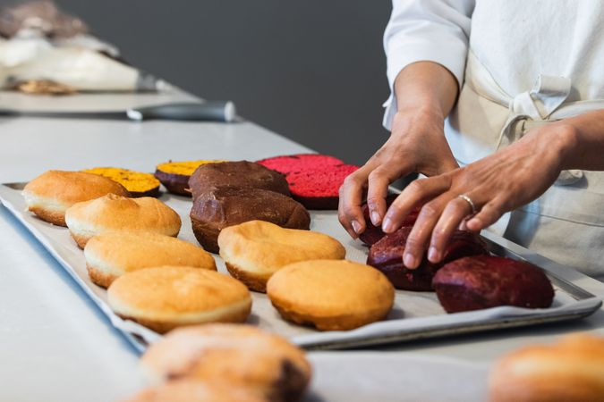 Crop cook putting sponge cakes on tray in kitchen