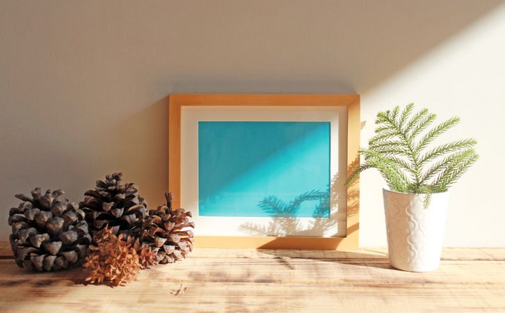 Wooden picture frame with blue interior mockup on desk with shadow