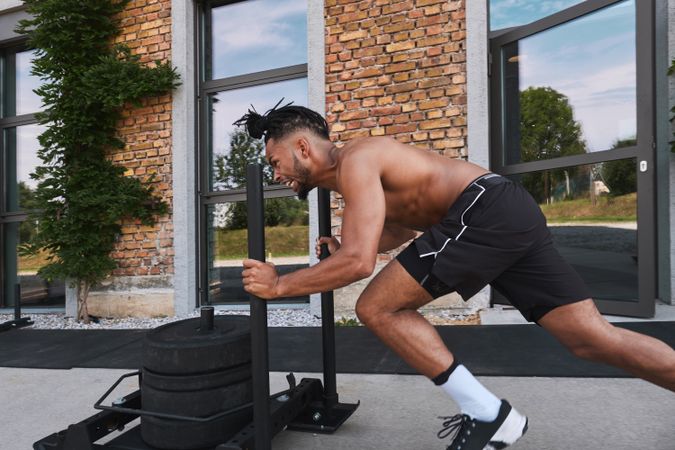 Black guy pulling weights in outdoor gym