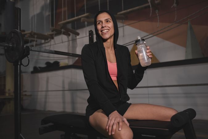 Smiling woman with bottle of water in gym