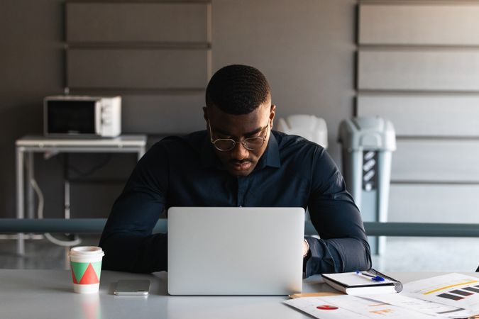 Black guy video chatting on tablet near laptop in workplace