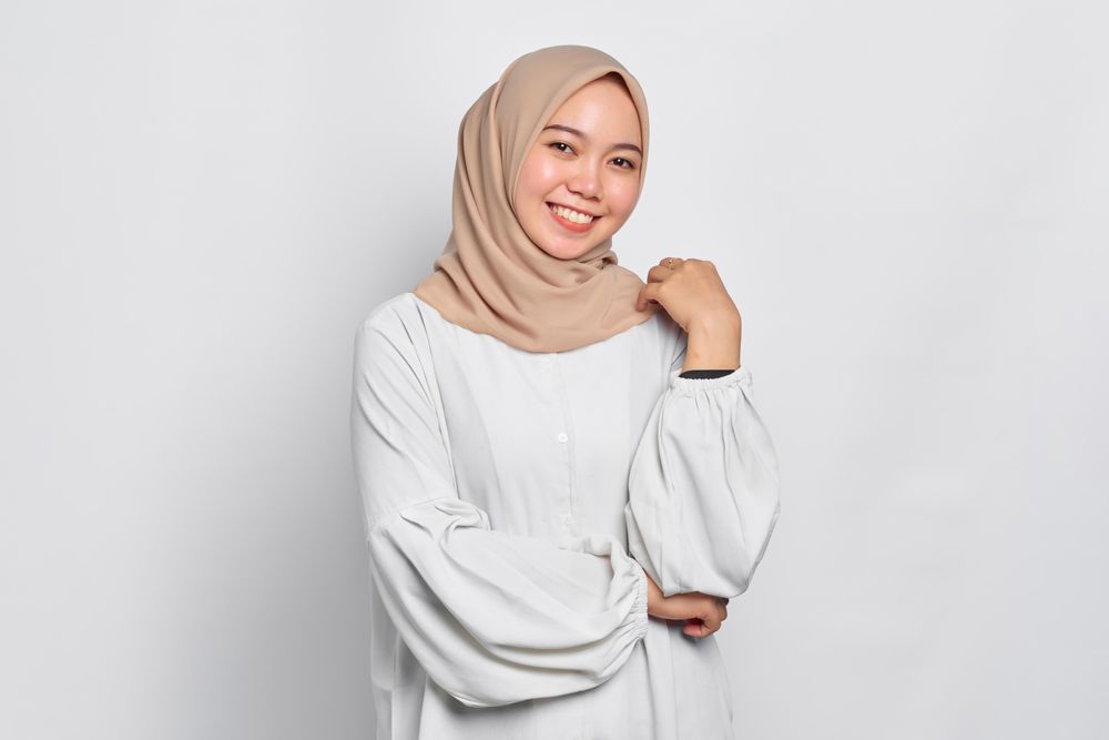 Smiling Asian female in headscarf with arm up