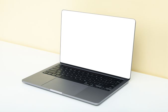 Open laptop with blank mockup screen against the wall in cream room