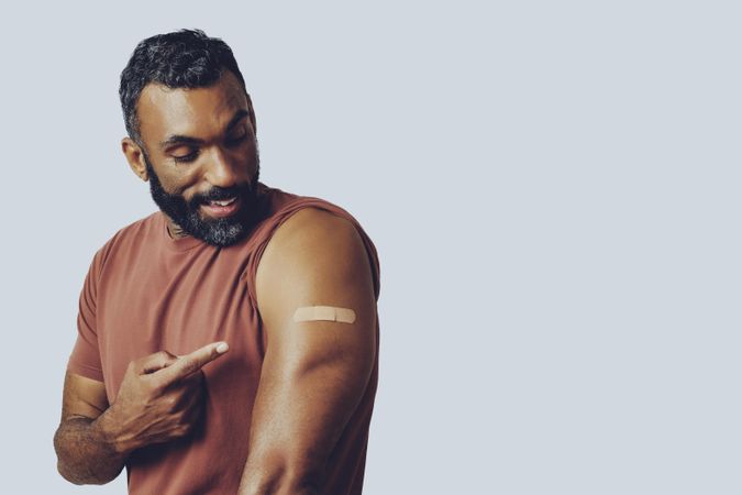 Smiling man pointing at vaccination with copy space