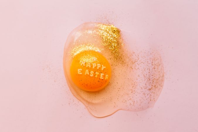 Raw broken egg with glitters on table