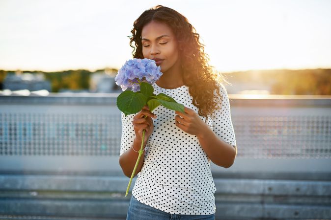 Beautiful Black woman with a blue flower on a sunny rooftop