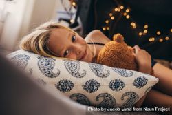 Smiling girl lying on bed holding her toy bGxzY0