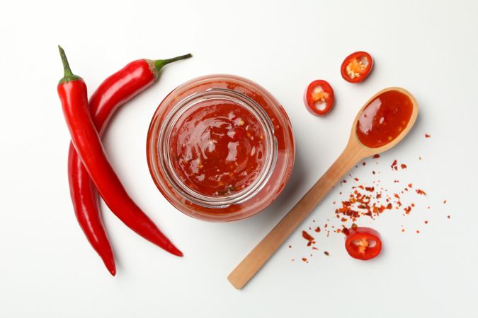 Composition with chilli pepper, spice and sauce on studio background