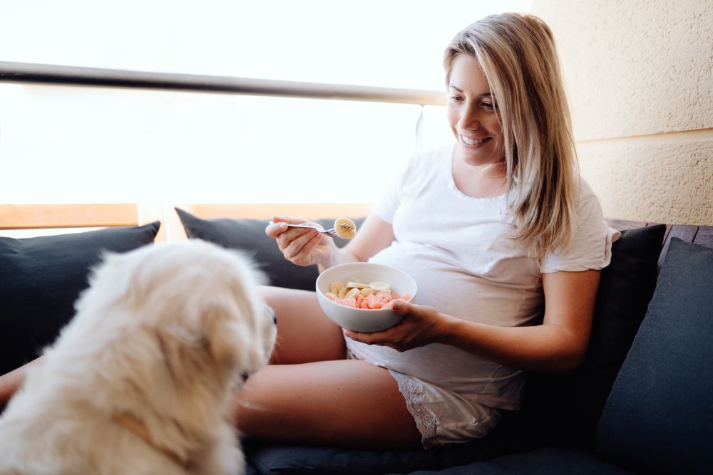 Smiling pregnant woman chilling with dog