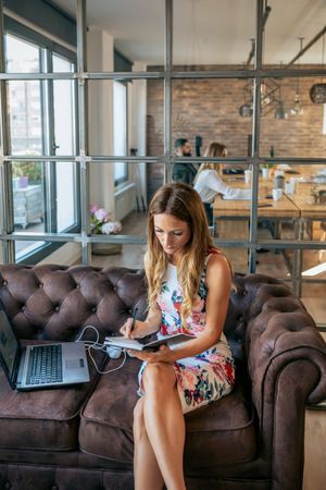 Businesswoman taking notes sitting on the sofa