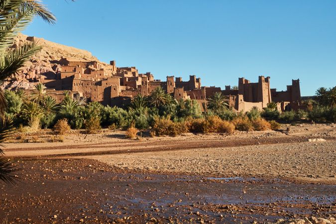 Ancient stone buildings near palms and water