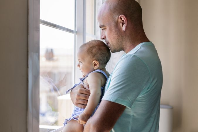 Father with baby looking out window