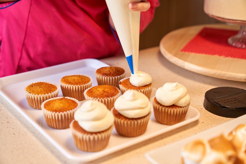 Crop confectioner icing cupcakes with buttercream