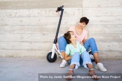 Woman and preteen girl outside talking together with a scooter with copy space 5qe315
