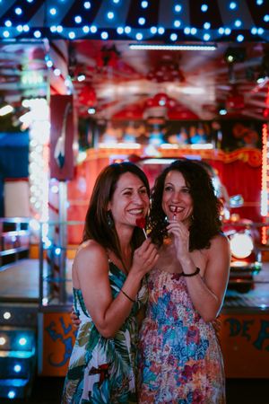 Girlfriends with lollipops in amusement park